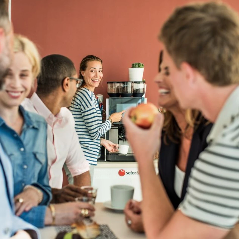 A group of people enjoying office coffee made with a tabletop coffee machine
